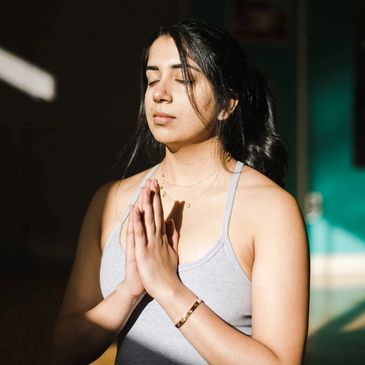 Woman meditating with eyes closed and hands in prayer position.