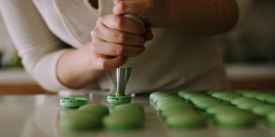 Piping green filling onto macarons.