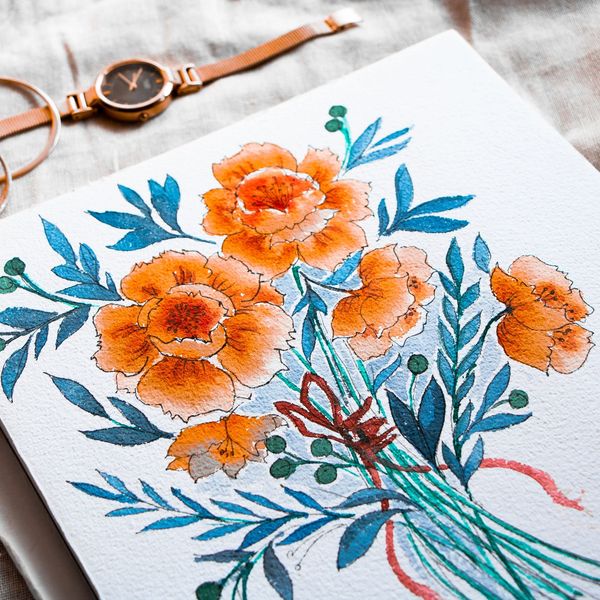 Watercolor painting of orange flowers with blue leaves on paper.