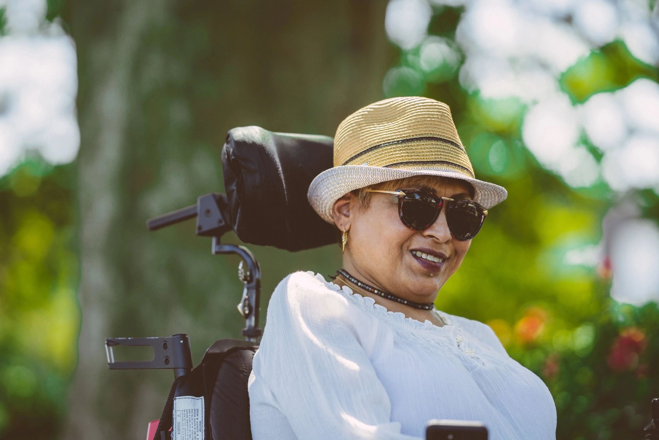 Lady smiling sitting in a power wheelchair with neck support