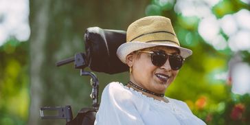 A woman in a wheelchair outdoors smiling