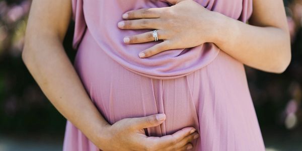 woman holding pregnant belly in purple dress