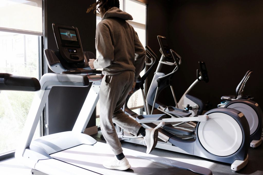 Person jogging on a treadmill in a modern gym.
