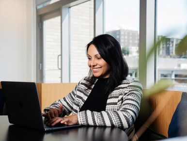 Woman working happily on laptop in a bright office space.