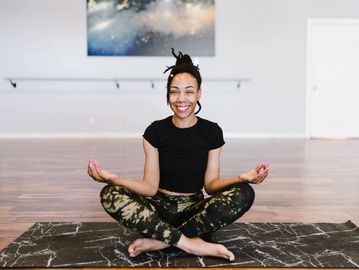 Woman seated cross-legged in a yoga studio smiling
