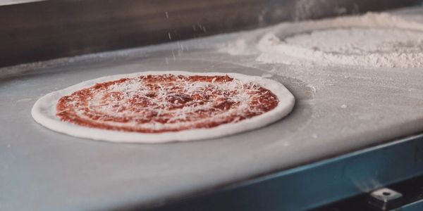 A pizza being made on a preparation table.