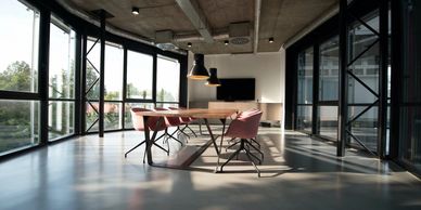 Modern office meeting room with large windows and sunlight.