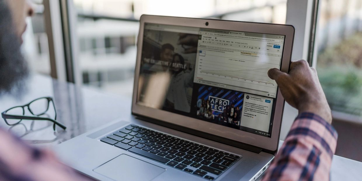 Person viewing charts and AfroTech page on laptop.