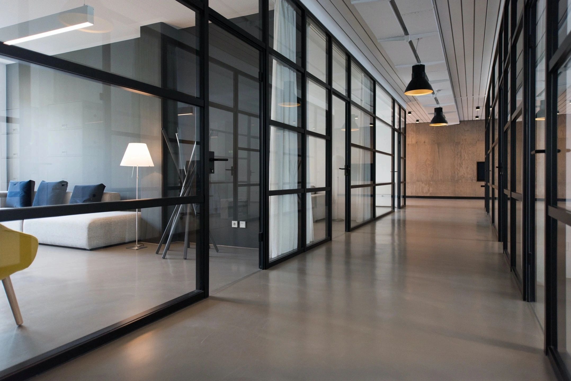 Modern office hallway with glass partitions and minimalist design.