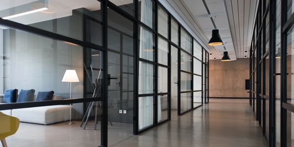 Modern office corridor with glass walls and minimalist decor.