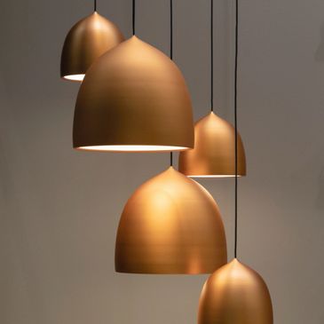 Elegant copper pendant lights with a smooth, rounded design hanging from the ceiling.