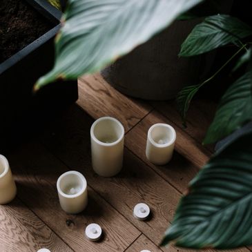 Candles on a wooden floor under a tall plant