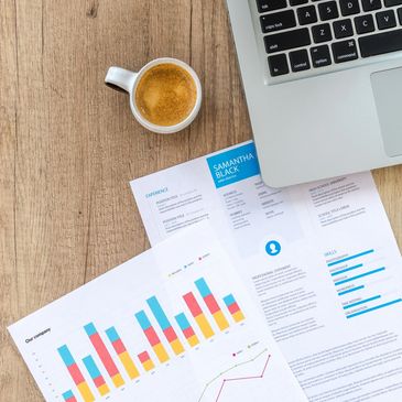 Coffee cup next to laptop and charts.