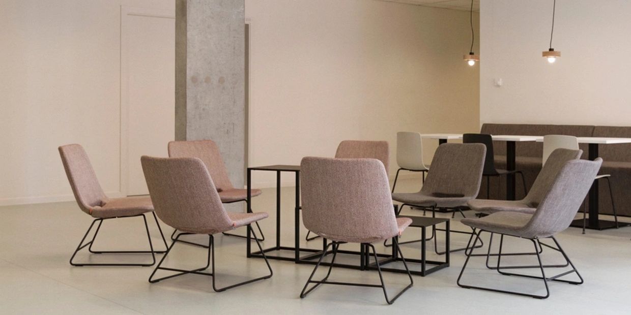 Modern chairs around small tables in a minimalist room.