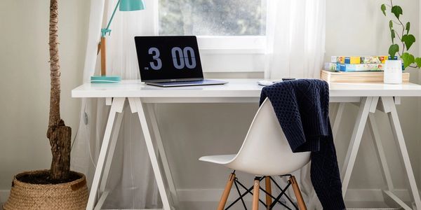 Bright, minimalist home office setup with plants and a modern chair.