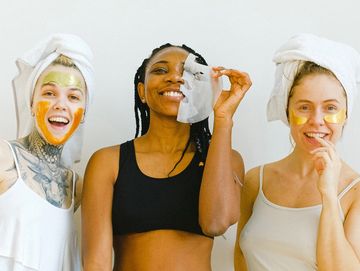 Three happy teenagers with white head wraps and masks on their faces.