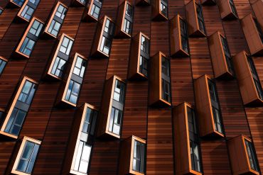Modern wooden building facade with protruding windows in geometric pattern.