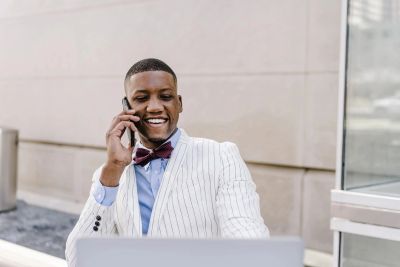 Young man in a striped suit smiling while talking on phone.