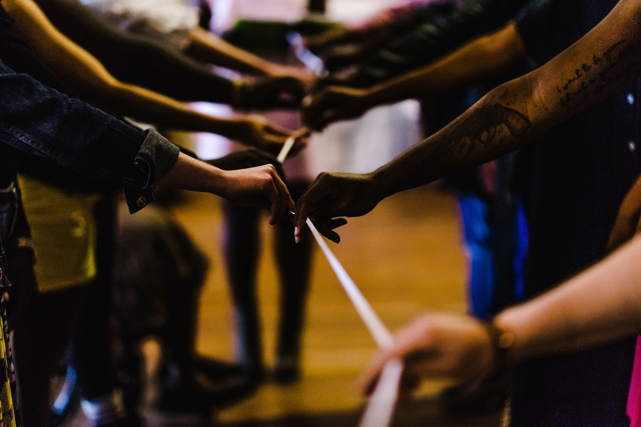 Hands holding a rope in a dimly lit setting.