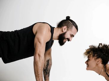 Man and woman smiling while doing push-ups facing each other.
