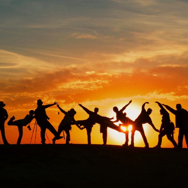 Group of friends playfully posing against a vibrant sunset sky.