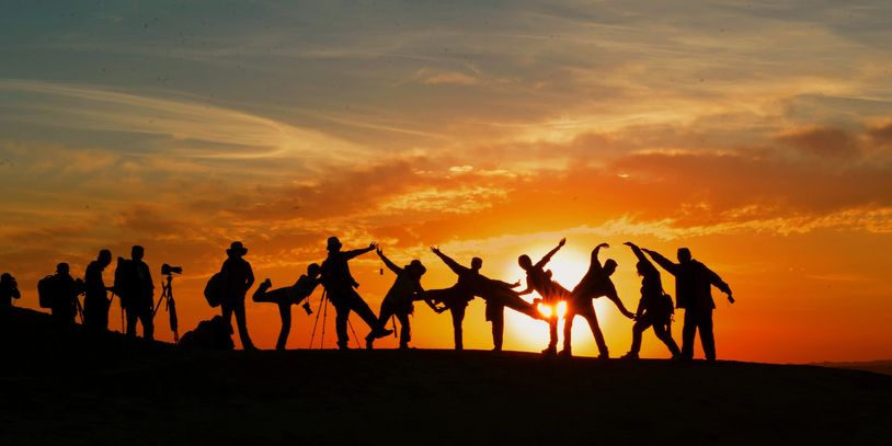 Silhouettes of people posing and photographing during sunset.