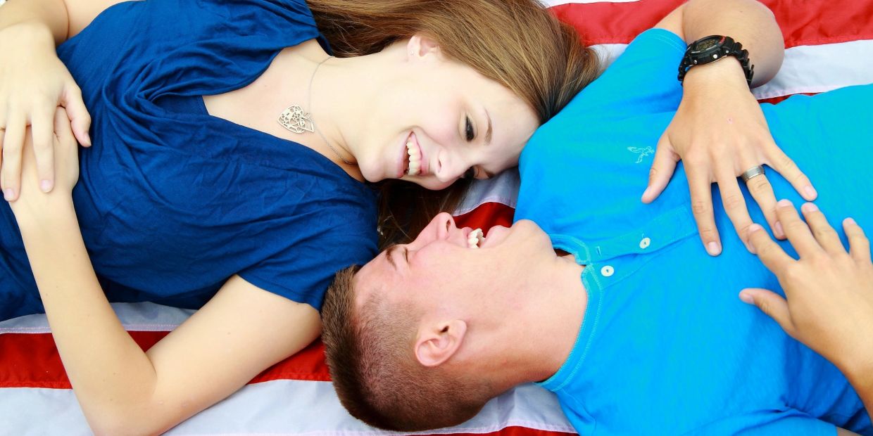 A happy couple lying on a striped blanket, gazing at each other with smiles.