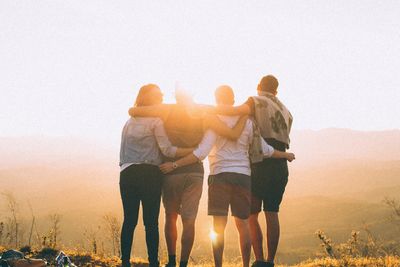 a group of four people watching sun set 