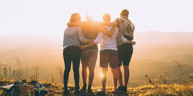Four friends embracing while watching sunset.