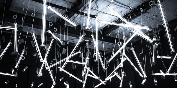 Abstract hanging fluorescent tube lights in a dark room.