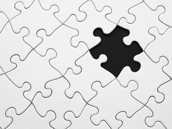 White jigsaw puzzle with one piece missing, revealing a black gap.