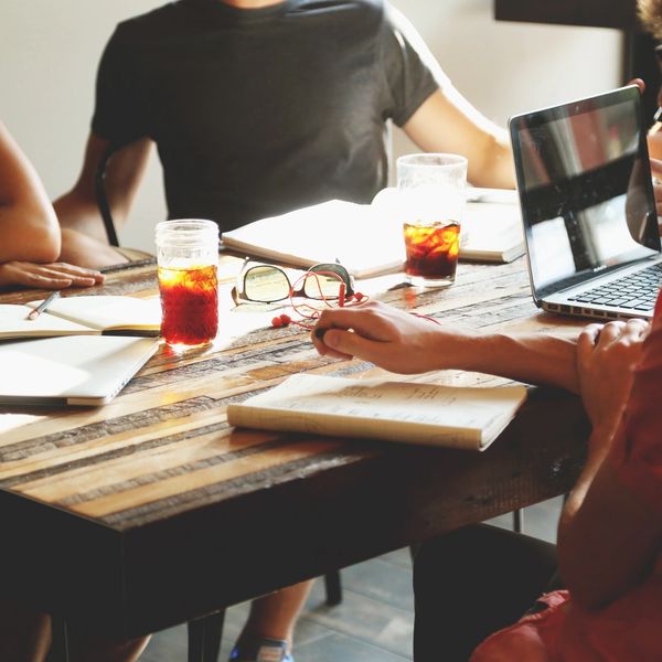 A group of businesspeople sitting at a table considering how to handle their payroll services.