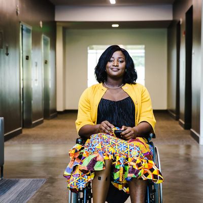 Woman in a wheelchair wearing a colorful skirt and yellow cardigan.
