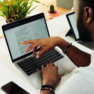 Person working on a laptop with a document open, pointing at the screen.