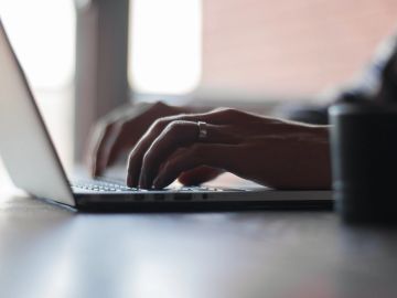 Hands typing on a laptop keyboard.