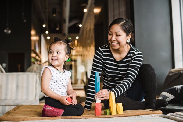 Mother and daughter playing with colorful blocks indoors.