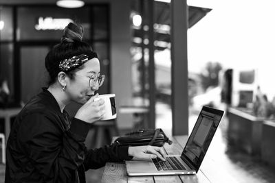 Woman working on laptop while drinking coffee.