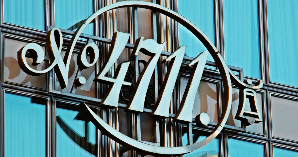 A metallic sign displaying 'No. 4711' on a glass building facade.