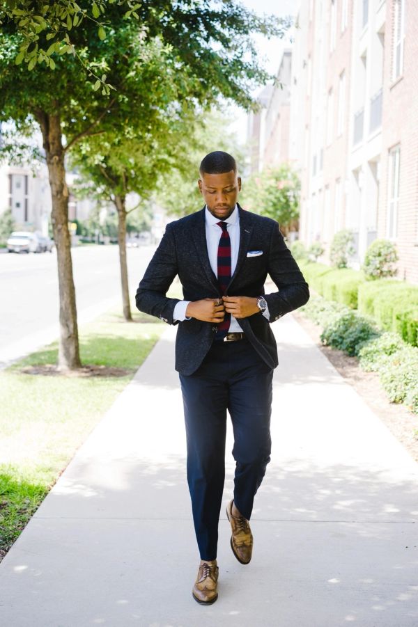 Man in a suit walking on a sidewalk.