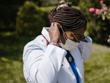 Doctor adjusting face mask outdoors.