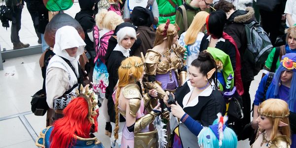 A group of cosplayers dressed in various fantasy and anime costumes at a convention.