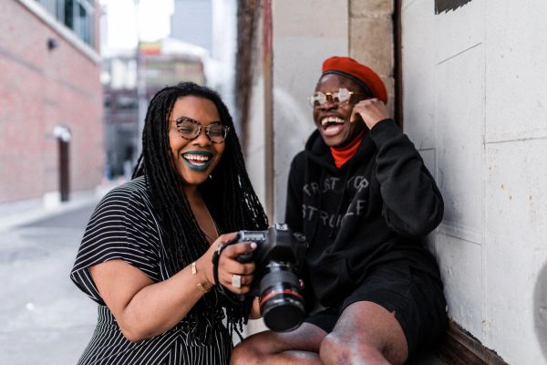 Two friends smiling and enjoying a moment with a camera.