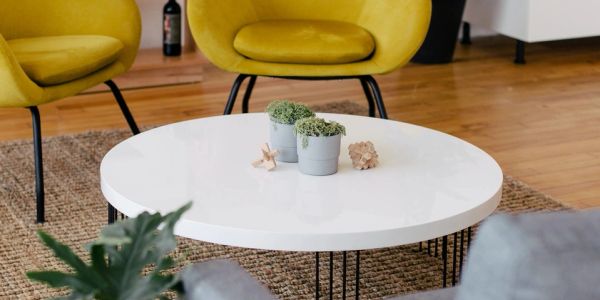 Modern living room with yellow chairs and a white round table.