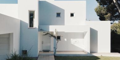Modern white minimalist house with geometric design and small windows.