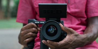Close-up of hands holding a RED digital camera.