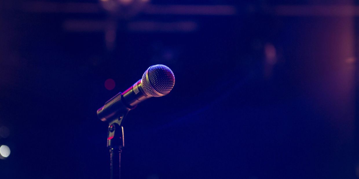 Close-up of a microphone on a stand with a dark background.
