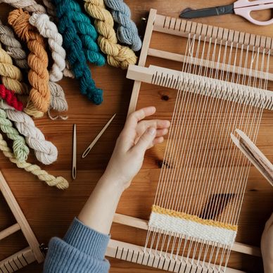 Hand weaving on a wooden loom with colorful yarns.
