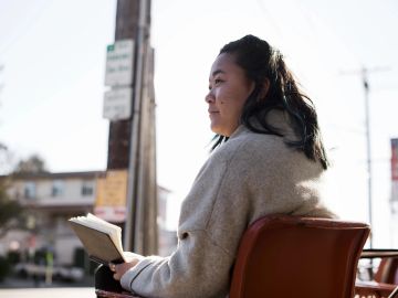 Woman sitting outdoors reading a book.