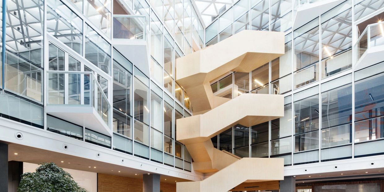 Modern office interior with wooden staircase and glass walls.