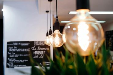 Close-up of hanging vintage light bulbs with a blurred background of a menu board.